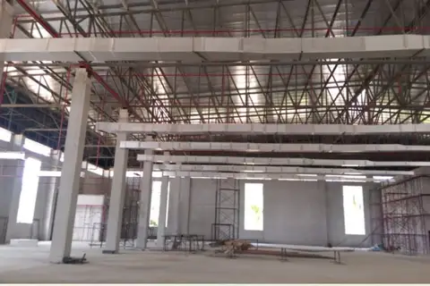 Land for Sale in Nong Pla Lai, interior of a large industrial building under construction with exposed beams and ductwork.