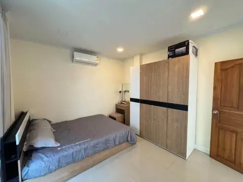 4 Bedroom House for Sale at Villa Asiatic bedroom with gray bedding, wooden wardrobe, and wall-mounted AC unit