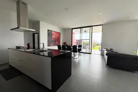 3 Bedroom House for Sale at The Prestige at Siam Royal View: Open-plan living area with kitchen island, dining table, and sofa, opening to the patio.