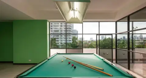 Jomtien Complex: Large outdoor swimming pool with blue tiles, surrounded by tall white condo buildings and ocean view.