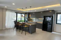 4 Bedroom House for Sale & Rent in Bang Lamung modern kitchen with dark grey cabinets, marble island, bar stools and pendant lights
