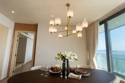 3 Bedroom Condo for Sale at Arom Wongamat dining area with white floral centerpiece and coastal skyline view
