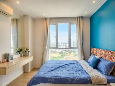 1 Bedroom Condo for Sale at Grande Caribbean bedroom with blue wall, floral headboard, and panoramic city view window