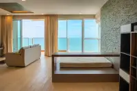 2 Bedroom Condo for Sale at Cetus Beachfront bedroom area with platform bed, stone accent wall, and panoramic ocean views