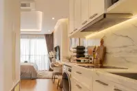 Studio Condo for Sale at Seaspire Jomtien white kitchen with marble backsplash, built-in washer, and open living area beyond