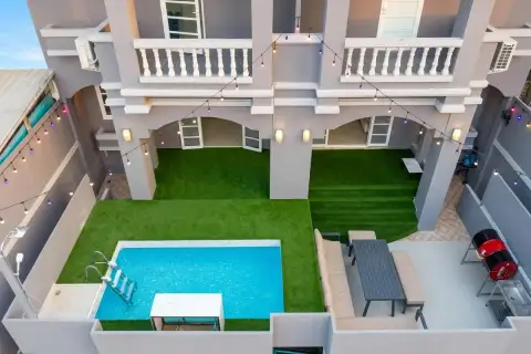 10 Bedroom House for Sale in Bang Lamung aerial view of courtyard pool, artificial turf, outdoor seating, and multi-storey facade with string lights