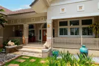4 Bedroom House for Sale & Rent in Bang Lamung covered front porch with Thai elephant statues, stone decor, and garden