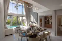 5 Bedroom House for Sale at The Lake Huay Yai open-plan dining area with dark glass table, ring pendant light, and pool view beyond