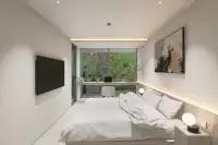 1 Bedroom Condo for Sale at Celine Wongamat bright bedroom with double bed, wall-mounted TV, desk, and floor-to-ceiling garden view window