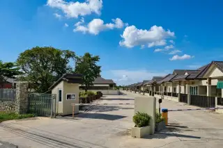 Victory Park gated entrance with a security booth and a long row of houses under a blue sky.