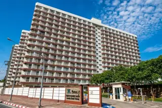 Rimhad Jomtien Condominium exterior view with multiple balconies, street-level entrance, and security gate under blue sky.