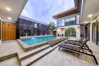 6 Bedroom House for Sale at M Mountain Village pool deck with sun loungers, jet fountains, and dark marble feature wall at twilight