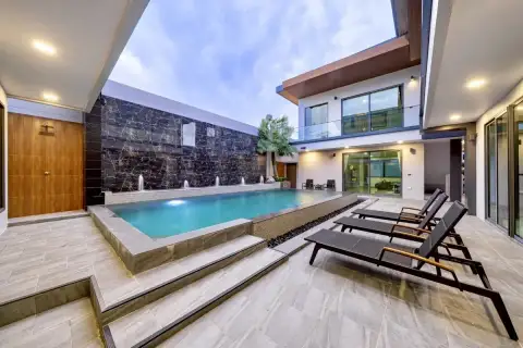 6 Bedroom House for Sale at M Mountain Village pool deck with sun loungers, jet fountains, and dark marble feature wall at twilight