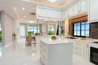 4 Bedroom House for Sale at Chokchai Garden Home 2, open-plan kitchen with white and gold cabinets, island, and dining area.