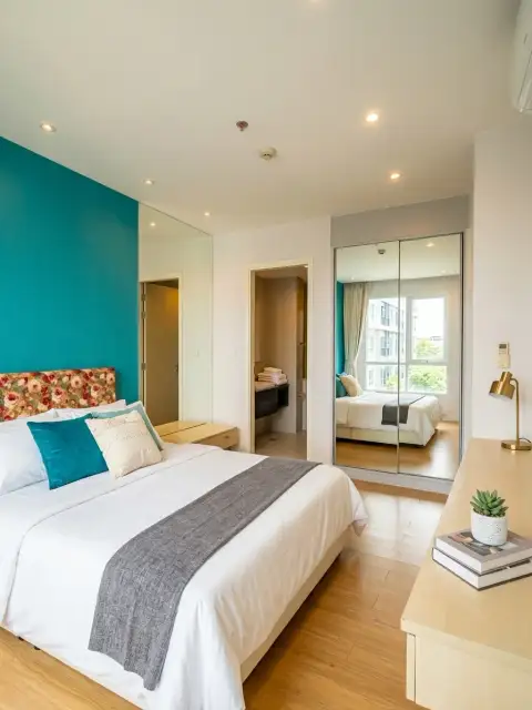 1 Bedroom Condo for Sale at Grande Caribbean master bedroom with teal accent wall, mirrored closet, and ensuite bathroom