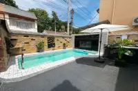 3 Bedroom House for Sale in Bang Lamung outdoor pool area with dark stone patio, sun umbrella, jacuzzi and tropical plants