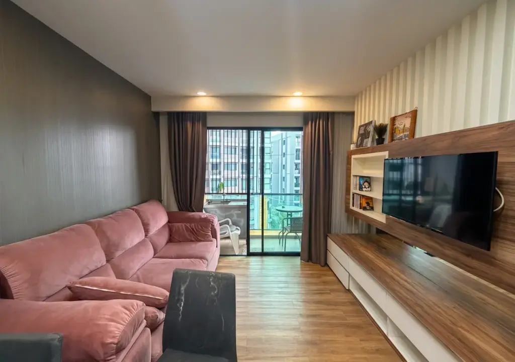 2 Bedroom Condo for Sale at Dusit Grand Park 1 living room with pink sofa, wall-mounted TV and balcony view