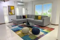 5 Bedroom House for Rent at Casa Jomtien bright living room with L-shaped grey sofa and colorful rug
