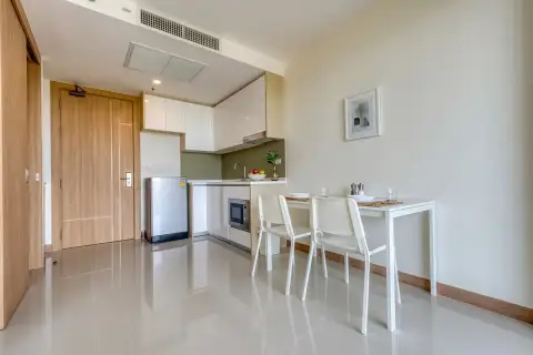 1 Bedroom Condo for Sale at The Riviera Jomtien compact kitchen and dining area with light wood doors.