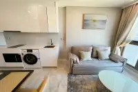 1 Bedroom Condo for Rent at Copacabana Beach Jomtien white gloss kitchen with washing machine and grey sofa in living area