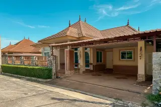 Censiri Home by Sirisa: Exterior view of a house with a brown tiled roof, yellow walls, stone fence, and green tree.