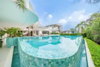 8 Bedroom House for Sale in Huai Yai curved infinity pool with teal mosaic tiles and lush tropical garden