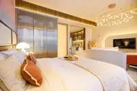 1 Bedroom Condo for Sale at Arom Jomtien king-size bed with warm lighting, glass wardrobe doors, and TV lounge beyond