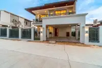 3 Bedroom House for Sale in Huai Yai two-storey front exterior with gated entrance and covered carport at dusk