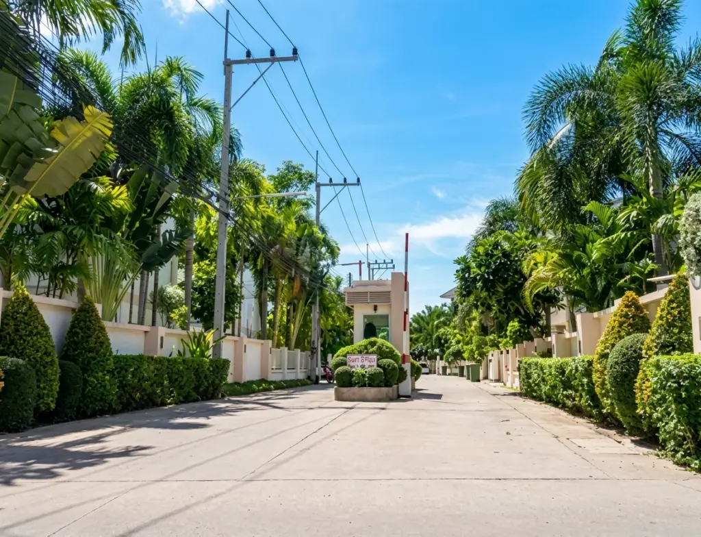 The Meadows gated community entrance with security barrier, lush palm trees, and manicured hedges.