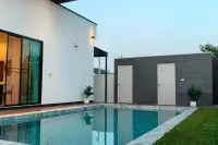 4 Bedroom House for Sale in Nong Prue, swimming pool with adjacent storage rooms and green lawn.