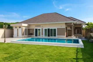 Living Grand Home single-story house with private swimming pool and green lawn under a clear blue sky.