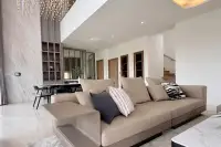3 Bedroom House for Rent at Horizon By Patta living area with large beige sofa, marble accent wall, built-in shelving, and staircase