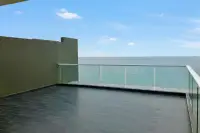 3 Bedroom Condo for Sale at Del Mare wide open terrace with glass railing overlooking the sea under a clear blue sky