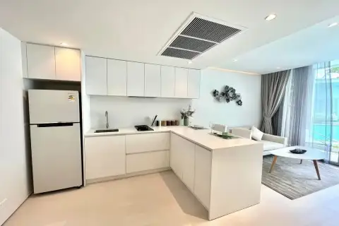 1 Bedroom Condo for Sale at Celine Wongamat modern white L-shaped kitchen with upper cabinets, fridge, and open living area