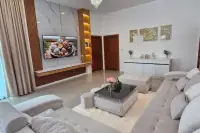 4 Bedroom House for Sale in Nong Prue, stylish living room with large TV, marble wall, and comfortable sofa.