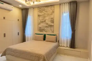 SP Village 1 master bedroom with double bed, marble-effect feature wall panel, built-in wardrobe, and sheer curtains