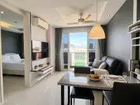 1 Bedroom Condo for Sale at MaxxCity Condo open-plan living room with TV, dining table, and bedroom view