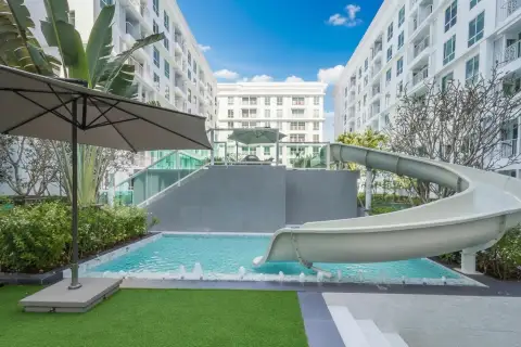 The Orient Resort & Spa outdoor swimming pool area with a water slide and surrounding lush greenery.