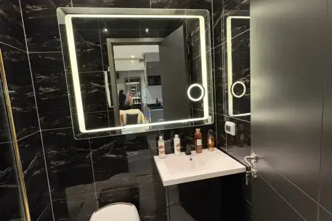 1 Bedroom Condo for Sale at Zenith Pattaya bathroom sink with lighted mirror and toiletries