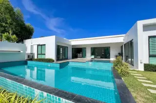 Palm Lakeside Villas rectangular swimming pool with lounge chairs, green lawn, and modern house with sliding glass doors.