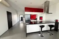 3 Bedroom House for Sale at The Prestige at Siam Royal View: Modern kitchen with black and white cabinets, red backsplash, and island with bar stools.