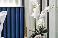 2 Bedroom Condo for Sale at Embassy Life bedroom detail with white orchids in silver vase beside blue upholstered headboard