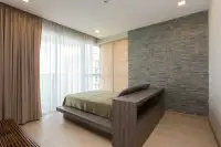 3 Bedroom Condo for Sale at Cetus Beachfront bedroom with platform bed grey stone accent wall and sheer curtained windows