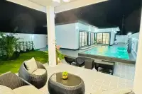 4 Bedroom House for Sale at Rattanakorn Village 18: Covered patio with seating overlooking the illuminated pool at night.