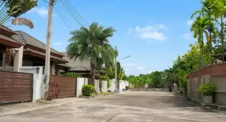 Baan Piam Mongkhon landscaped garden area with large rocks, palm trees, and green grass.