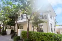 4 Bedroom House for Sale at Tadarawadi South Pattaya: Angled exterior view of the house with lush green trees and sunlight.