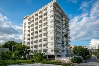 Royal Beach Condotel, exterior view of the tall white building with balconies from a street level, surrounded by trees.