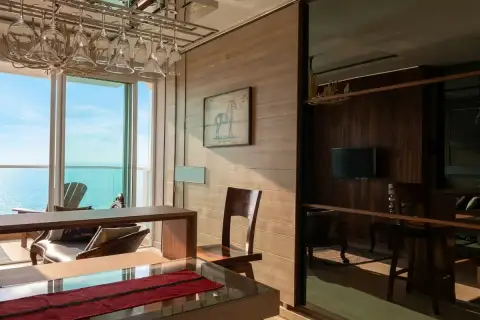 1 Bedroom Condo for Sale at Cetus Beachfront dining area with glass table, hanging wine glasses, wood-panel walls, and sea view