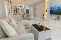 4 Bedroom House for Sale at Chokchai Garden Home 2, living room with a large L-shaped sofa, coffee table, and dining area.