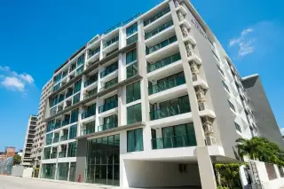 Aurora Pratumnak modern condo building exterior with multiple stories, balconies, large windows, and street view.